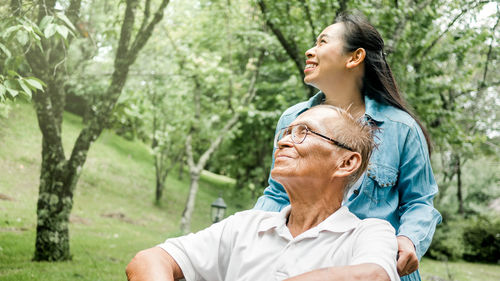 Rear view of couple looking away against trees