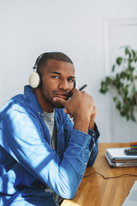 Side view portrait of man wearing headphones while sitting at wooden table