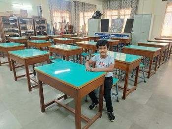 Rear view of boy sitting on table