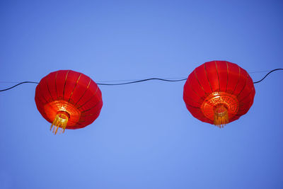 Low angle view of chinese lanterns against clear blue sky