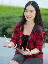 Portrait of smiling young woman sitting outdoors