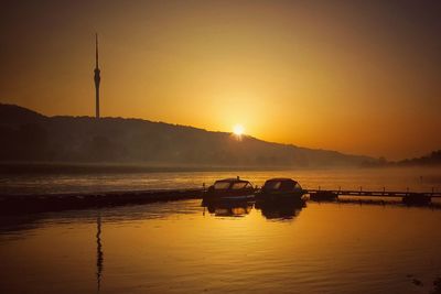 Silhouette boat in sea against sky during sunset