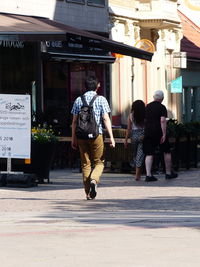 Rear view of people walking on footpath