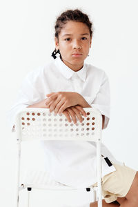 Portrait of young man sitting against white background