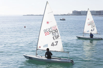People sailing on sea against sky