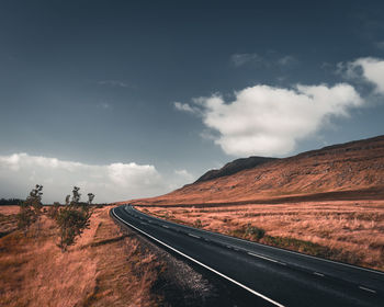 Road leading towards mountains against sky