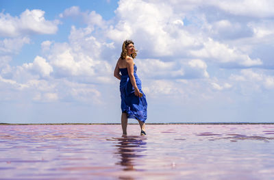 Rear view of woman standing at beach against sky