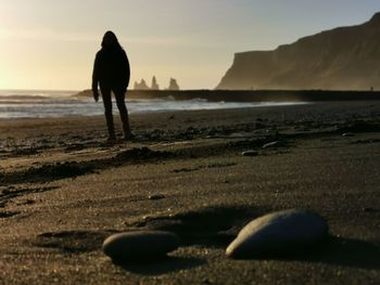 Silhouette man standing on beach against sky during sunset