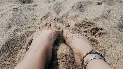 Low section of woman standing on sand at beach