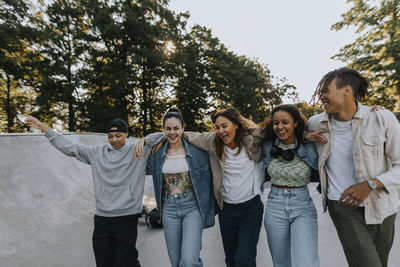 Happy teenagers walking together with arms around