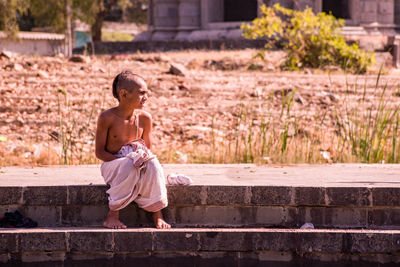 Full length of shirtless boy sitting on staircase