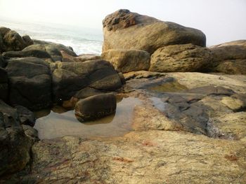 Rock formation at beach against sky