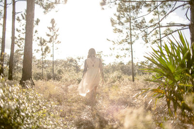 Rear view of woman standing against trees