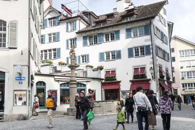 People walking on street amidst buildings in city