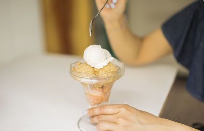 Cropped hands of woman having ice cream on table