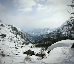 Scenic view of snowcapped mountains and houses covered by snow in gran paradiso national park, italy