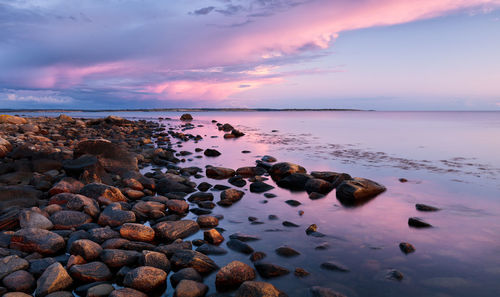 Rocks at sea shore against sky during sunset