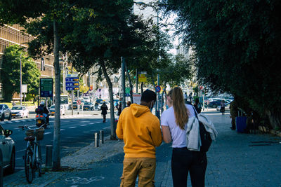 Rear view of people walking on road in city