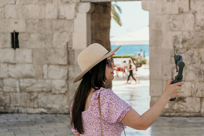 Midsection of woman holding umbrella standing against wall