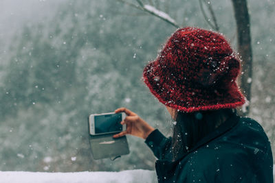 Rear view of man holding smart phone during winter