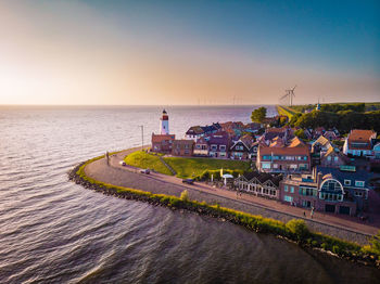 Buildings by sea during sunset