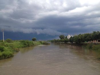 Scenic view of river against cloudy sky