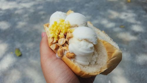 Close-up of cropped hand holding ice cream in hotdog bun