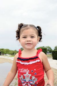 Portrait of cute girl standing at beach against sky