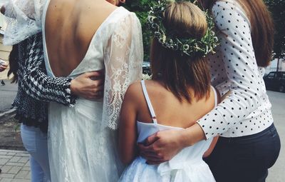 Rear view of bride with friends standing on road