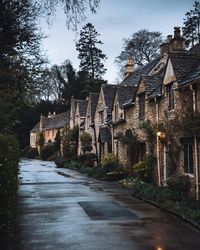 Footpath amidst trees and houses against sky