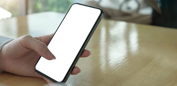 Midsection of person using smart phone on table