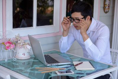 Young woman using mobile phone while sitting on table