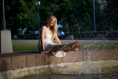 Full length of woman sitting by pond