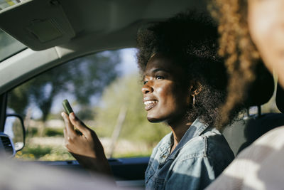 Smiling young woman using smart phone in car