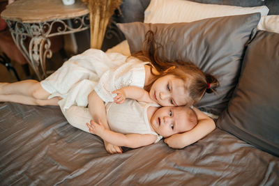 Girl hugs her younger sister on the bed