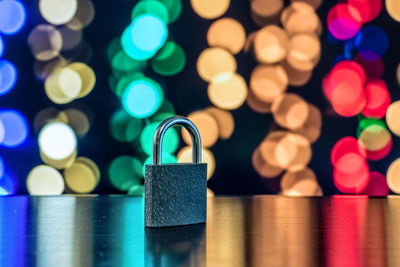 Close-up of padlock on table against colorful illuminated lights