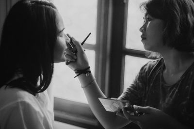 Woman applying make-up to friend at home