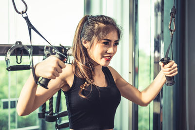 Smiling young woman exercising in gym