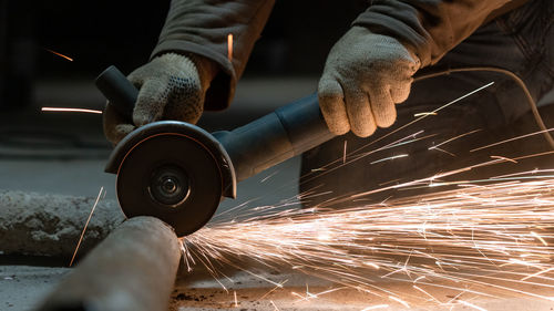 Cropped hands of man cutting metal in workshop