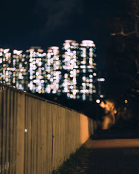 Illuminated footpath by building against sky at night