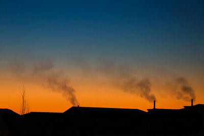 High section of silhouette houses against dramatic sky