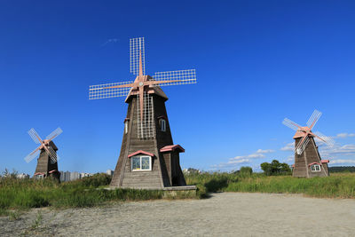 Traditional windmill on field against clear blue sky