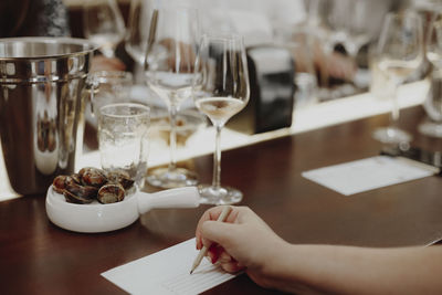 Midsection of woman holding wine glass on table