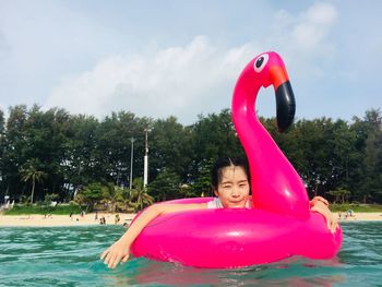 Young woman on flamingo inflatable ring in sea