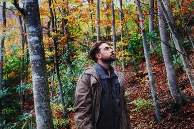 Young man looking up in forest