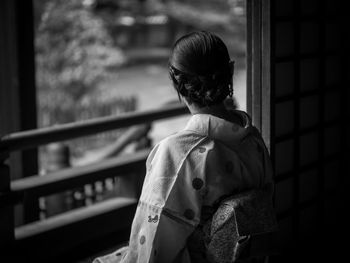 Rear view of woman in kimono standing in balcony