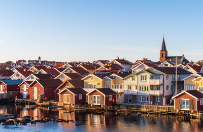 High angle view houses by river and buildings in town against sky