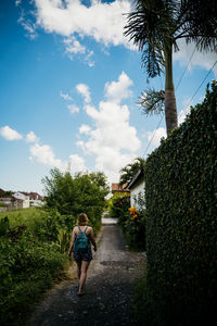 Rear view of woman walking on footpath in town