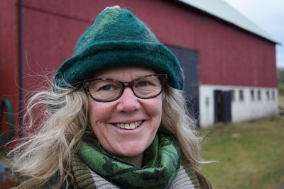 Portrait of smiling woman in hat against house