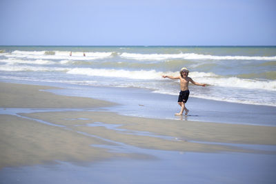 Full length of boy on beach against sky